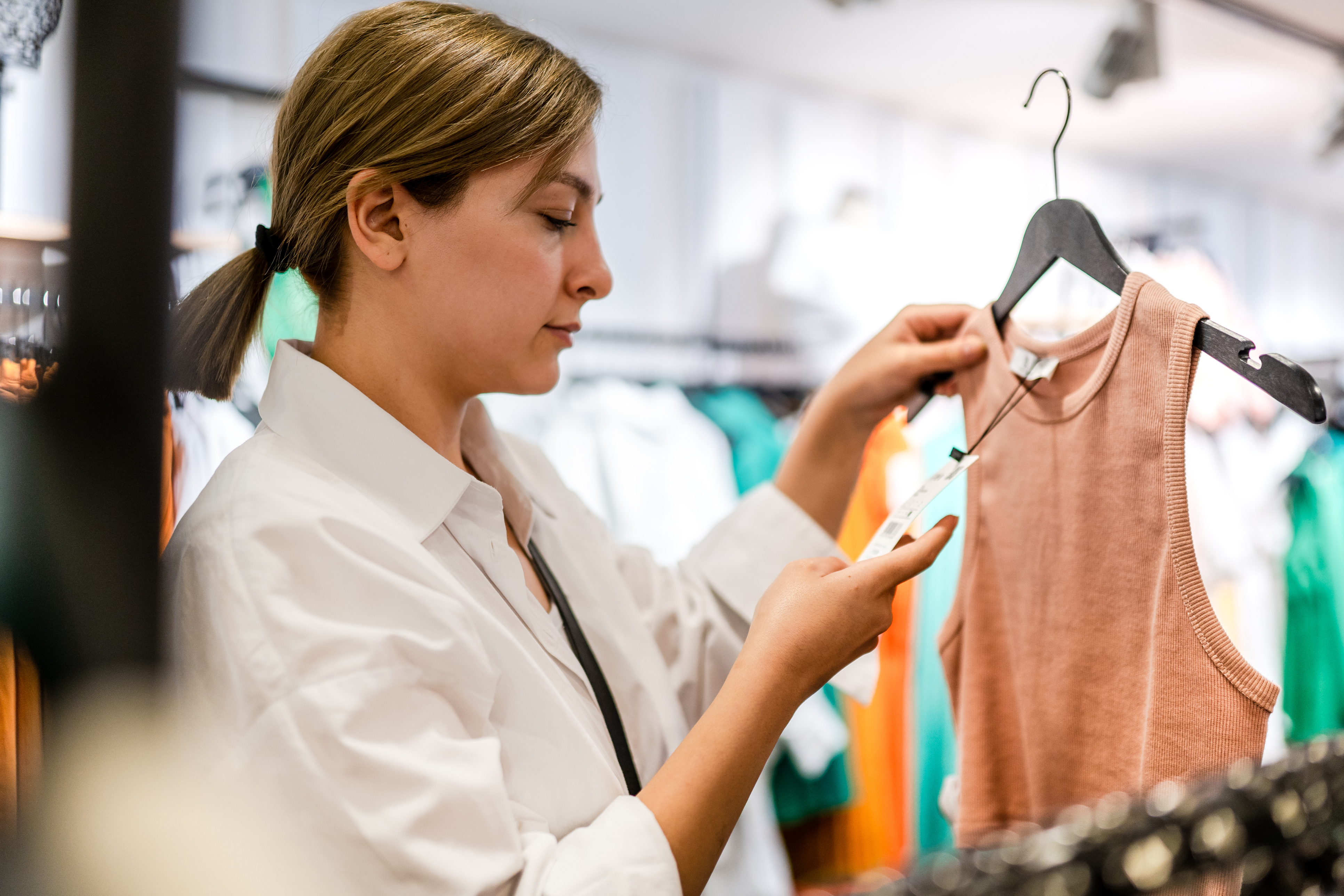 Woman checks price tag on tank top. 