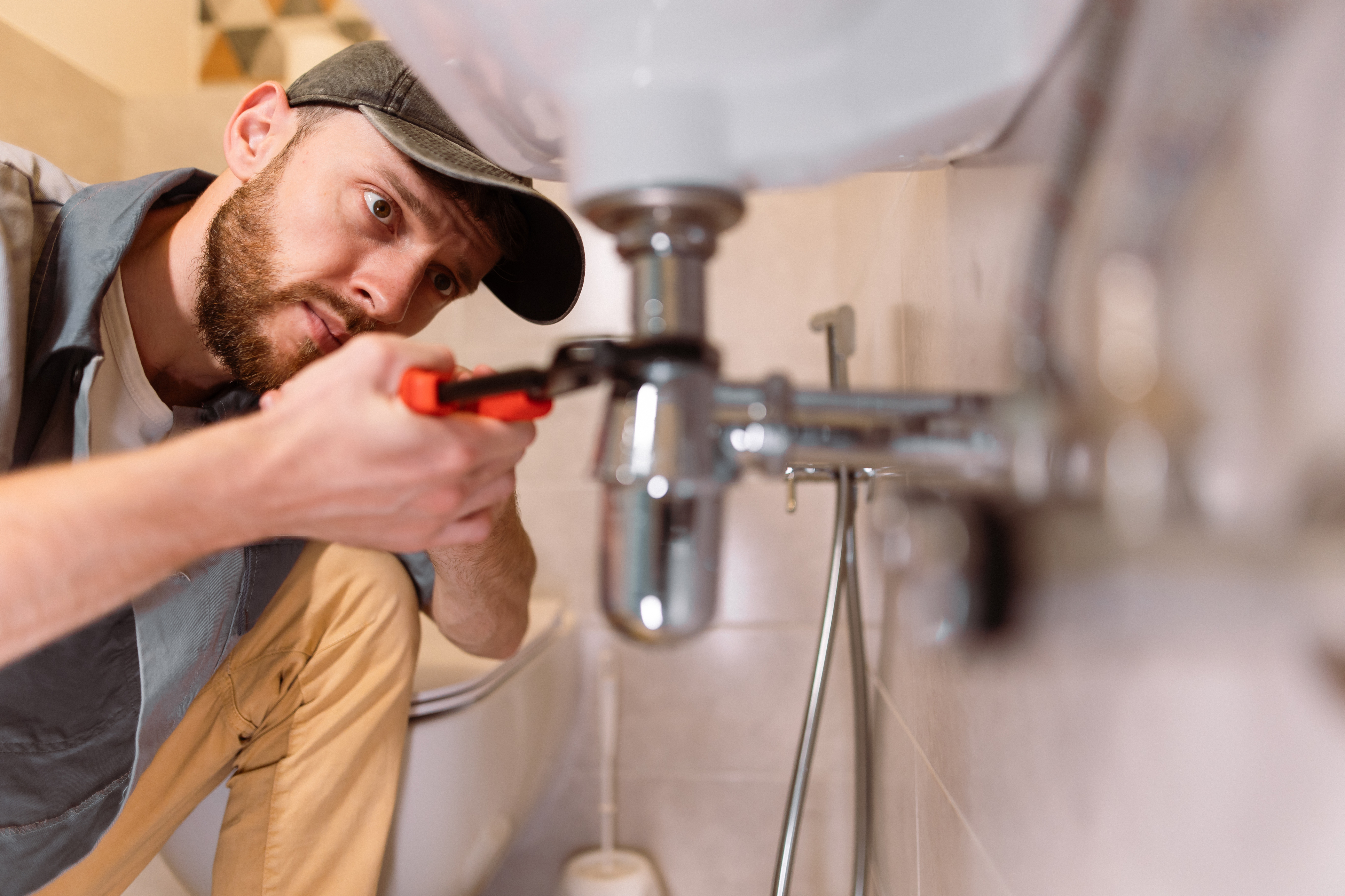 Plumber uses a tool to tighten a joint.