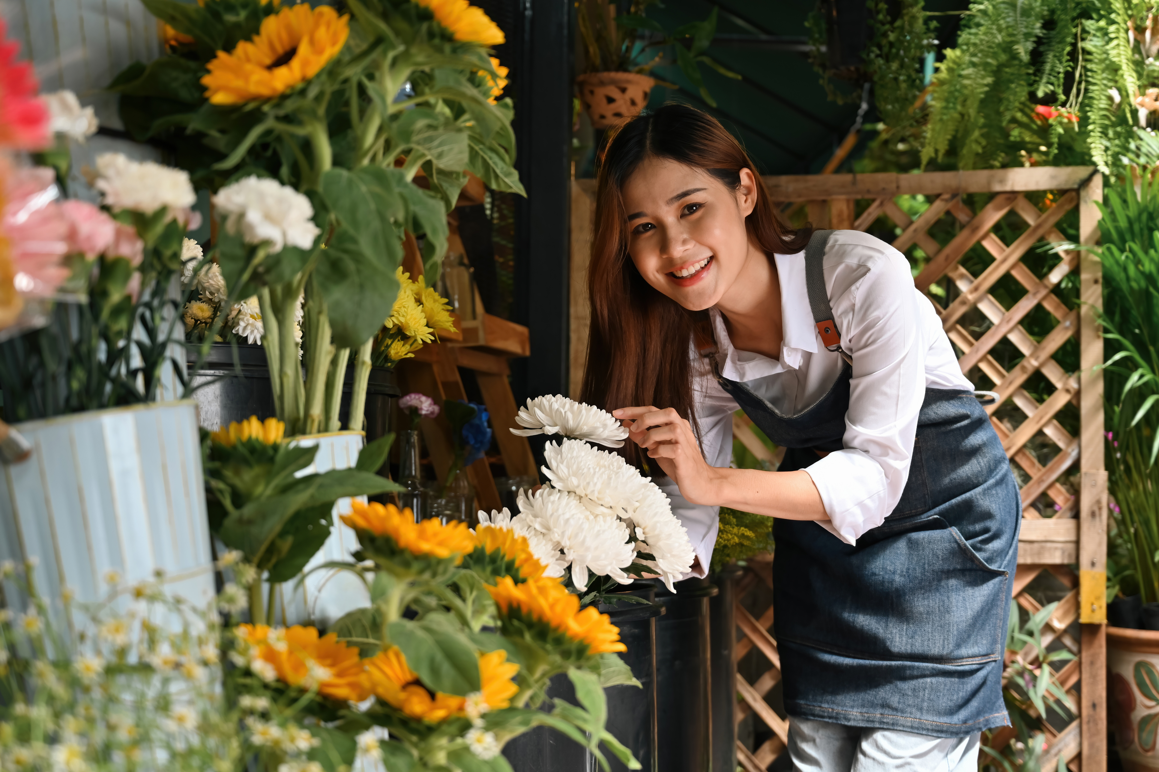 A floral shop owner arranging fresh flower display in store