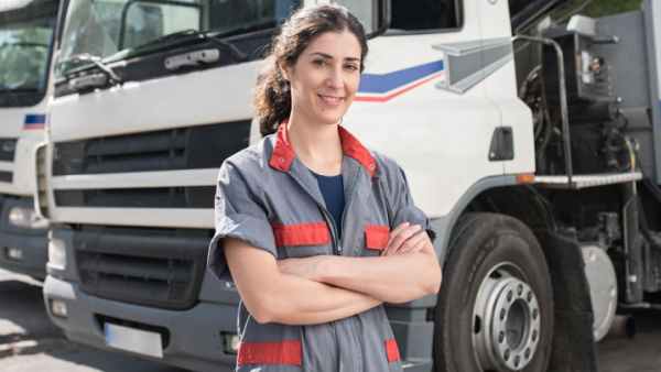 Truck driver stands in front of their vehicle