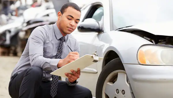 Auto insurance agent adjusting a car