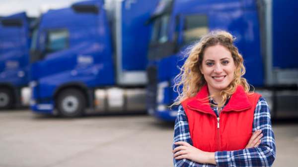 Truck driver stands in front of their vehicle